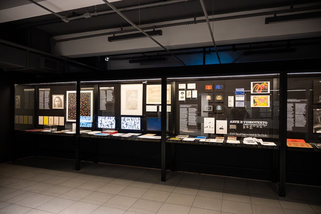 Vitrines iluminadas com documentos e imagens na exposição O Mundo Através da IA.