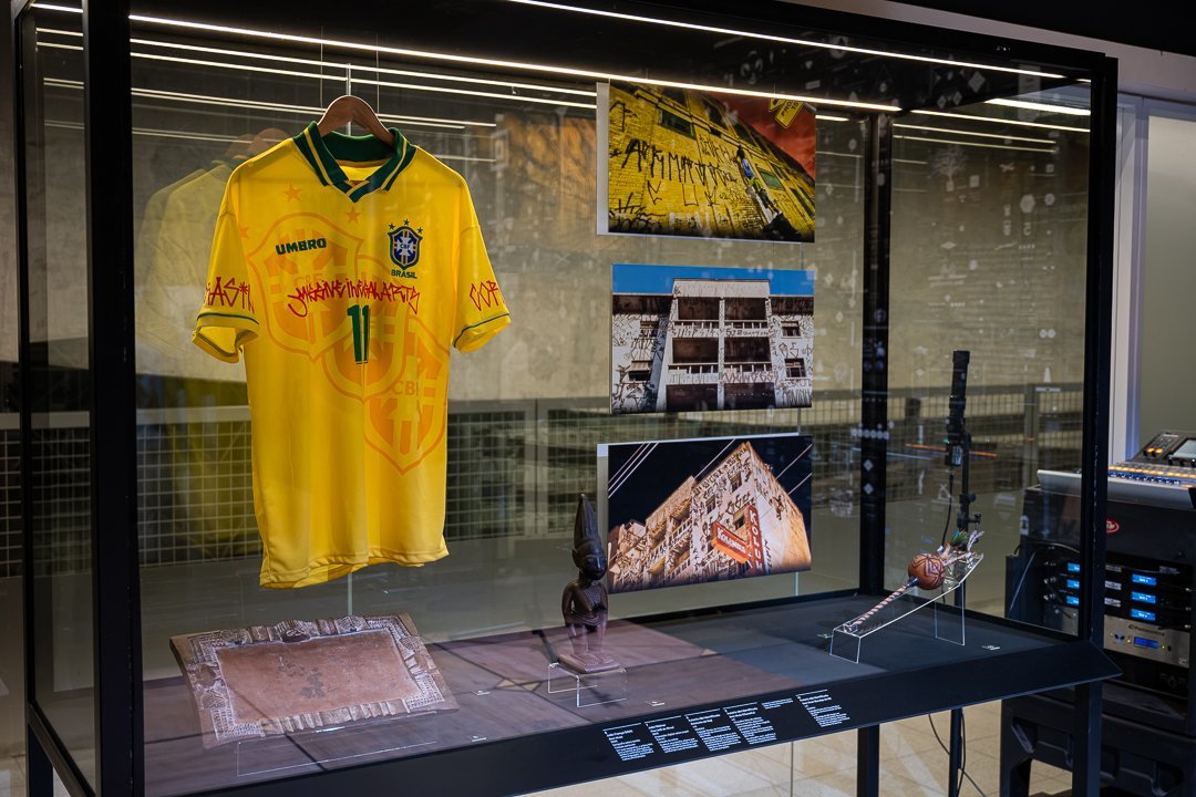 Vitrine com camisa da seleção brasileira, imagens e documentos. O Mundo Através da IA, Sesc 24 de Maio, São Paulo, 2026.