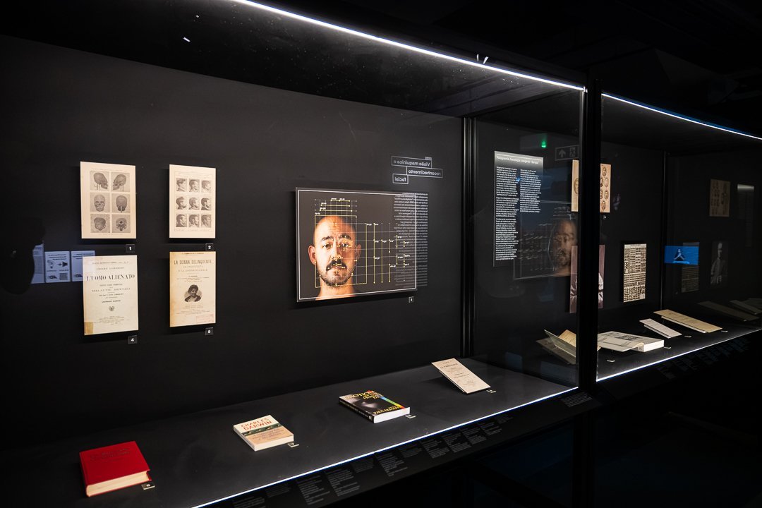 Detalhe de vitrine com estudos de rostos, retrato e documentos. O Mundo Através da IA, Sesc 24 de Maio, São Paulo, 2026.